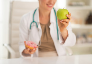Closeup on doctor woman choosing between apple and donut
